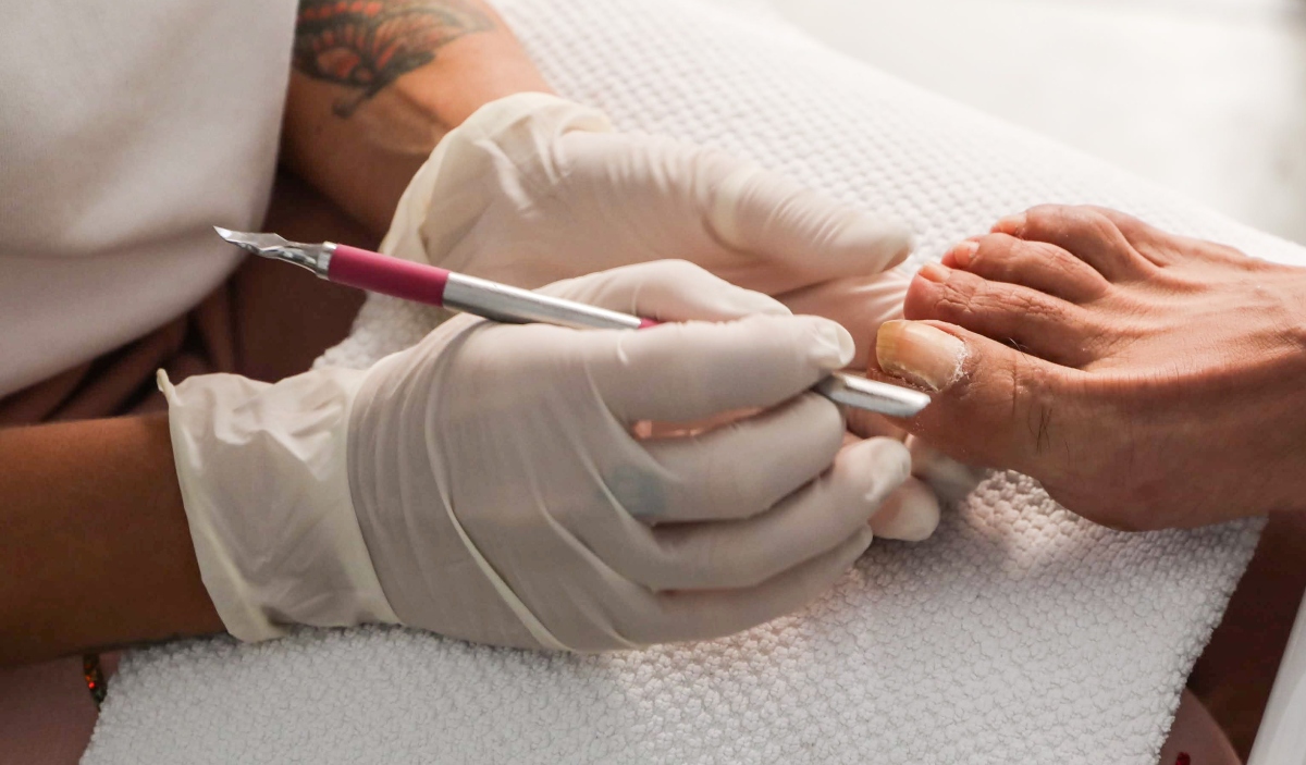 Pedicure verzorgt de teennagels en nagelriemen van een klant met professioneel gereedschap.